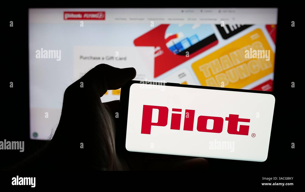 Allemagne. 6 mars 2025. Dans cette illustration photo, une personne tient un téléphone portable avec le logo de la société américaine Pilot Travel Centers LLC (Pilot Flying J) sur l'écran devant la page Web de l'entreprise. (Crédit image : © timon Schneider/SOPA images via ZUMA Press Wire) USAGE ÉDITORIAL SEULEMENT ! Non destiné à UN USAGE commercial ! Banque D'Images
