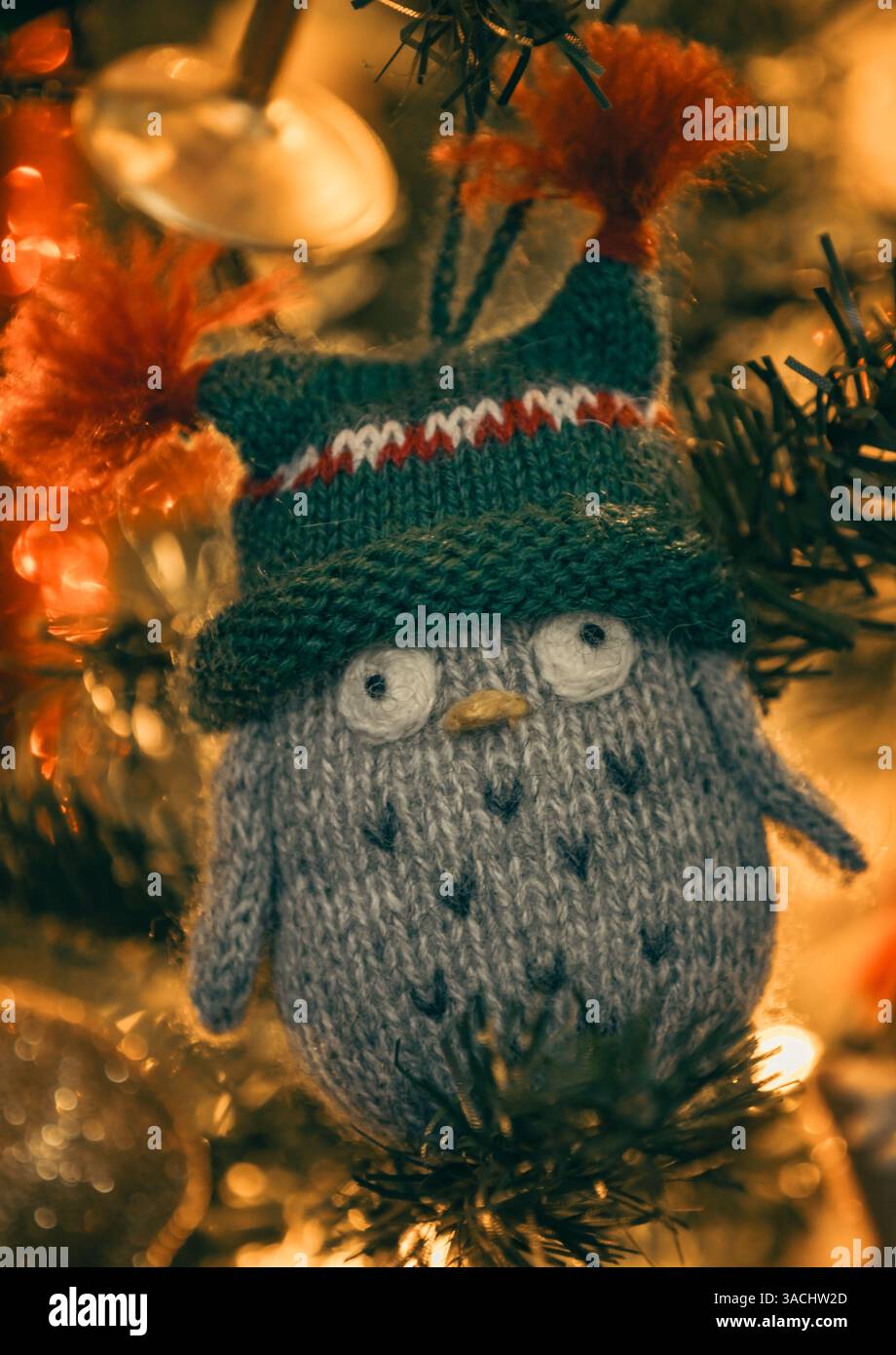 Décoration de Noël hibou tricoté dans un chapeau sur un arbre de Noël dans une lumière chaude Banque D'Images