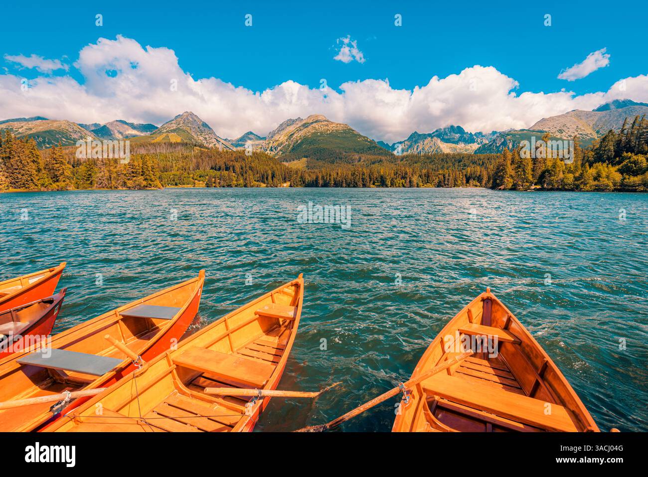 Bateau en bois de lac d'automne flottant sur l'eau calme, entouré de feuillage d'automne coloré, montagnes de ciel idylliques en arrière-plan, paysage naturel paisible Banque D'Images