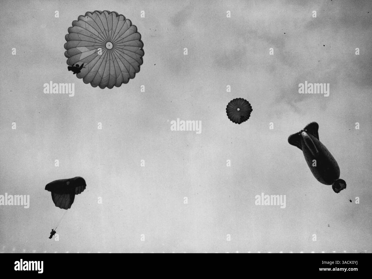 'Training in the Air' School for Parachutiers -- 'le ballon monte' -- maintenant' parachutistes à part entière, les volontaires sautent d'un ballon captif, à la RA.F. École, Upper Heyford. Au cours des deux dernières années et demie, près de 80 000 sauts d'entraînement ont été effectués à l'école, sans mort. Conçues pour jouer un rôle de plus en plus important dans l'armée du futur, les forces aéroportées britanniques reçoivent une formation hautement spécialisée dans l'art de la guerre depuis les nuages. À la fois à l'école pré-parachutiste d'Aldershot, et à l'école R.A.F. de parachutisme d'Upper Heyford, Oxfordshir Banque D'Images