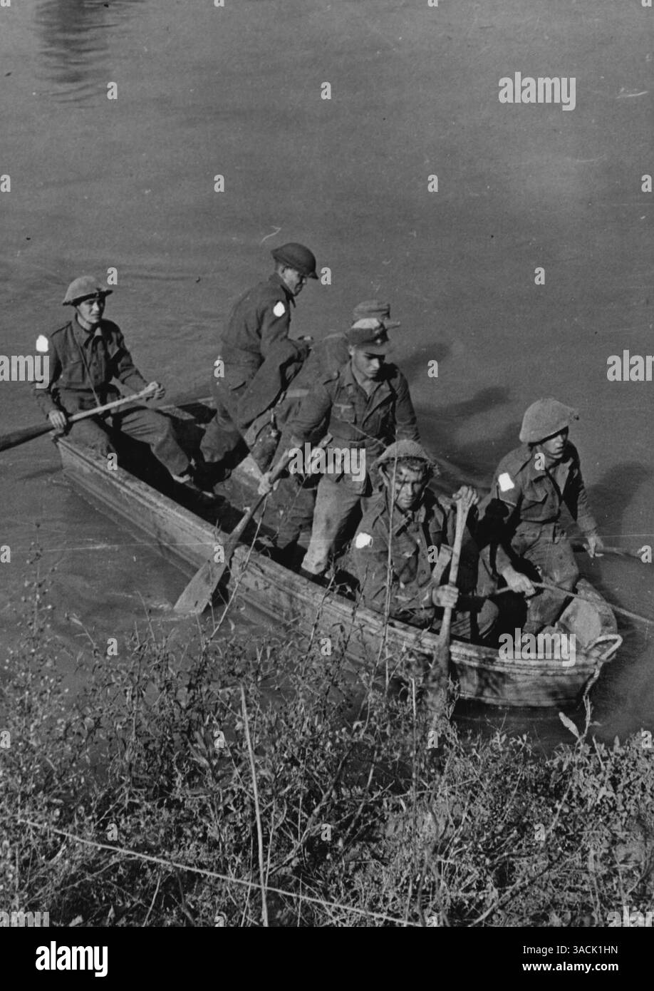 Cinquième Croix le Volturno -- pendant l'obscurité d'octobre 14/15 1943., la Cinquième armée a lancé sa grande attaque sur le fleuve Volturno. Bientôt, plusieurs têtes de pont sont entre les mains des Alliés, et les blindés commencent à faire une traversée de la rivière. Maintenant (19.10.43)., les forces alliées sont bien au-dessus de la rivière à plusieurs points et ont occupé la ville de Cancello, à environ six milles de la côte et de l'estuaire du Volturno après une lutte acharnée. Photo prise dans la lumière tôt le matin juste après le lancement de l'attaque sur le Volturno, montre : - « pagayer leur propre canoë » premiers prisonniers allemands capturés aidant à faire du ferry Banque D'Images Cinquième Croix le Volturno -- pendant l'obscurité d'octobre 14/15 1943., la Cinquième armée a lancé sa grande attaque sur le fleuve Volturno. Bientôt, plusieurs têtes de pont sont entre les mains des Alliés, et les blindés commencent à faire une traversée de la rivière. Maintenant (19.10.43)., les forces alliées sont bien au-dessus de la rivière à plusieurs points et ont occupé la ville de Cancello, à environ six milles de la côte et de l'estuaire du Volturno après une lutte acharnée. Photo prise dans la lumière tôt le matin juste après le lancement de l'attaque sur le Volturno, montre : - « pagayer leur propre canoë » premiers prisonniers allemands capturés aidant à faire du ferry Banque D'Images