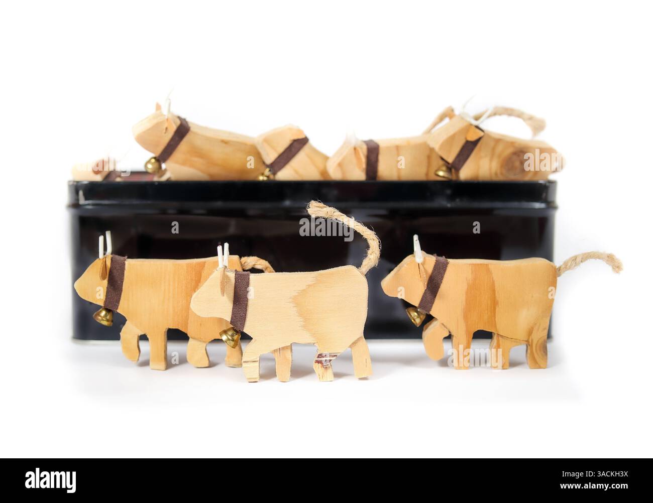 Beaucoup de vaches jouets devant la boîte à jouets défocalisée avec des vaches. Vue latérale de vaches laitières miniatures avec cloches. Concept d'industrie laitière, production de lait ou de viande. Banque D'Images