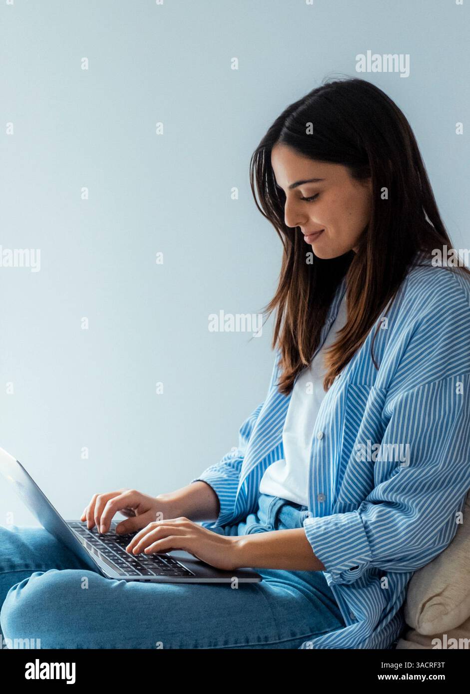 Jeune femme caucasienne couché sur un canapé dans le salon travaille en ligne sur un gadget portable. Une femme millénaire se repose sur un canapé à la maison. Regardez le message texte sur l'écran de l'ordinateur sur l'appareil. Concept de communication. Banque D'Images