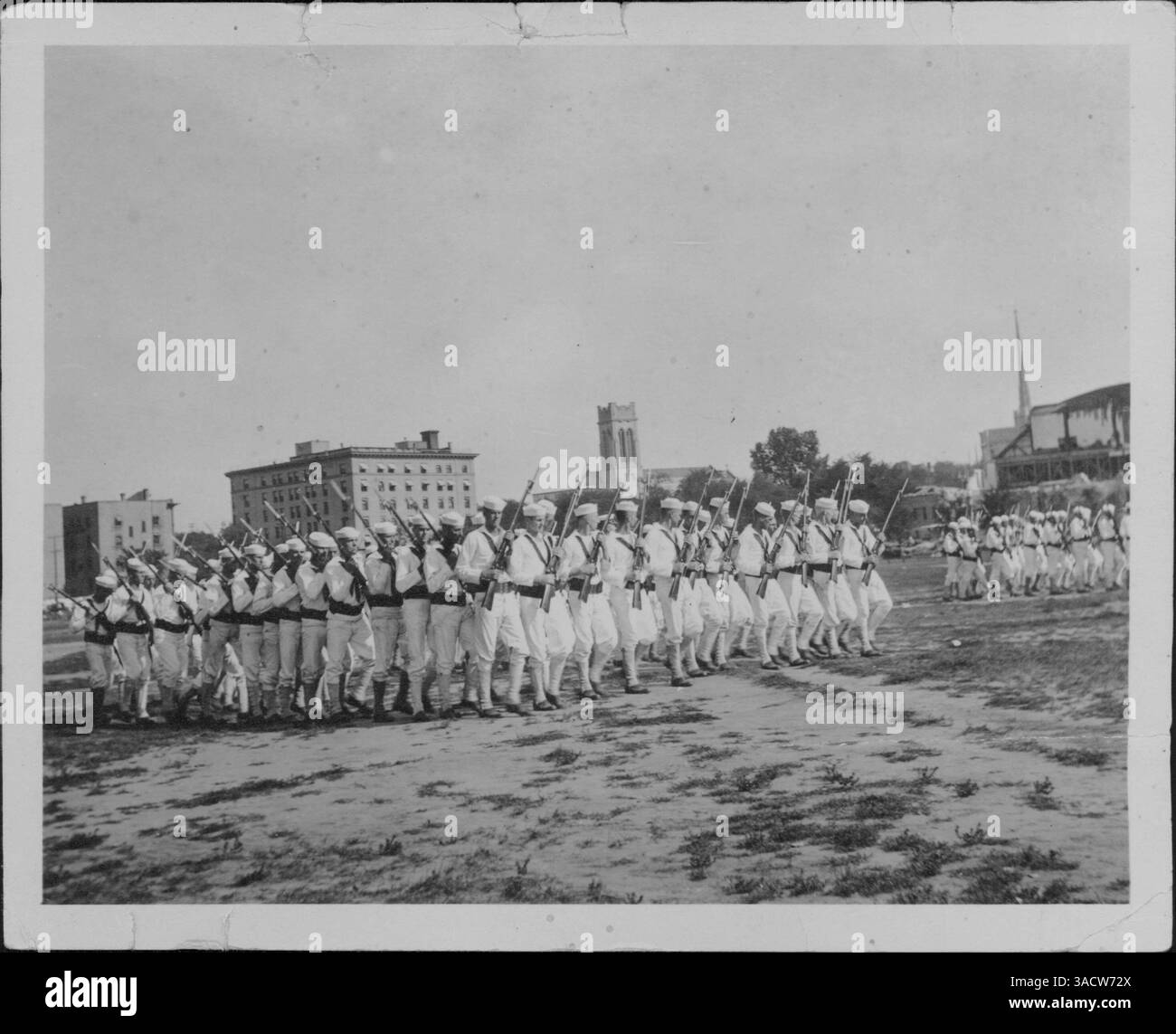 Cette image montre les Dunwoody Jackies marchant à Armory Field, avec le Plaza Hotel, l'église de marque et l'église méthodiste Hennepin Avenue en arrière-plan. La photo remonte à environ 1917-1918, reflétant un moment historique. Banque D'Images