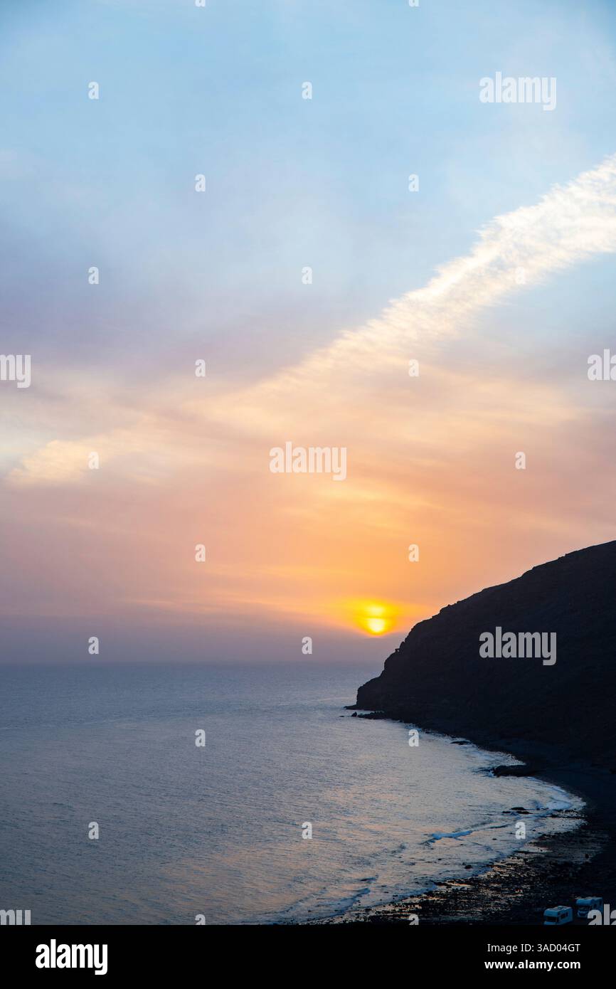 Coucher de soleil dans une baie. Beau paysage photographié avec une vue sur une côte aride à marée basse. À une lumière calima, sable du désert au crépuscule avec une grande couleur de ciel à Gran Tarajal, îles Canaries, Fuerteventura, Espagne Banque D'Images
