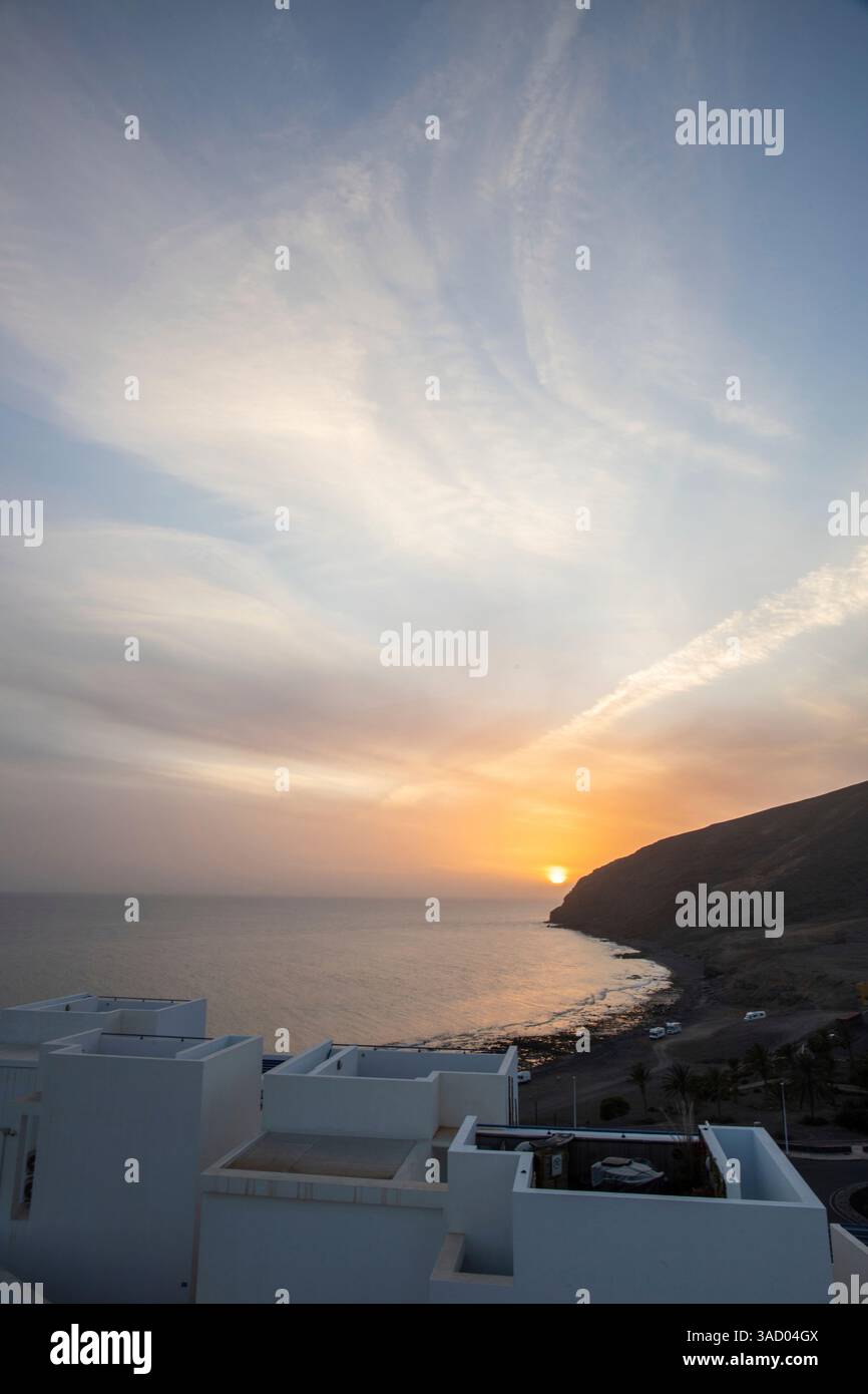 Coucher de soleil dans une baie. Beau paysage photographié avec une vue sur une côte aride à marée basse. À une lumière calima, sable du désert au crépuscule avec une grande couleur de ciel à Gran Tarajal, îles Canaries, Fuerteventura, Espagne Banque D'Images