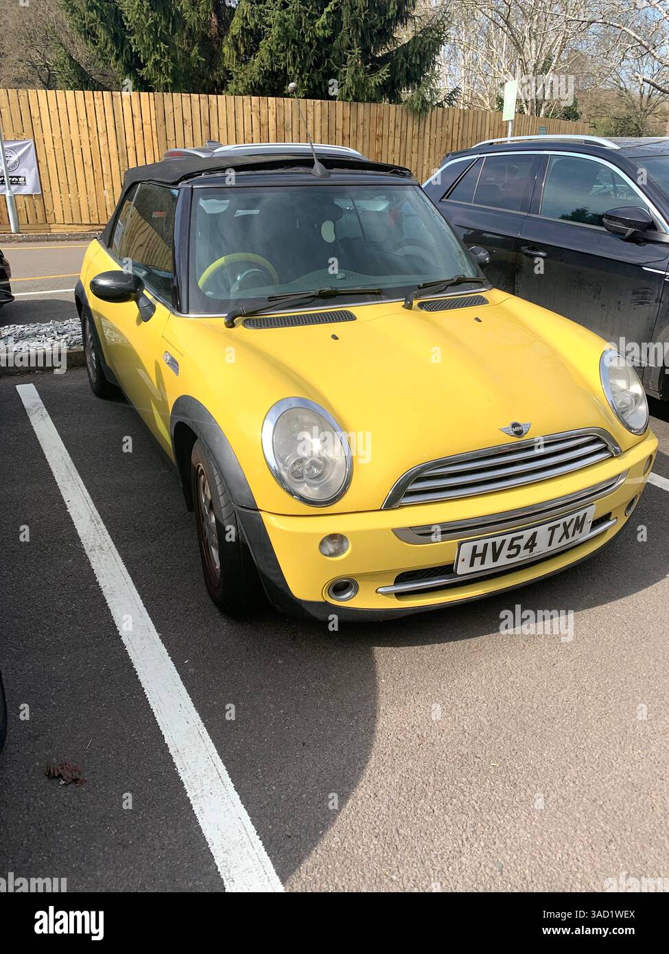 Mini voiture jaune British English soft top berline sport joli look jolies filles voiture tissu toit noir jaune parking parking Angleterre Anglais - Image de stock capturée avec un smartphone