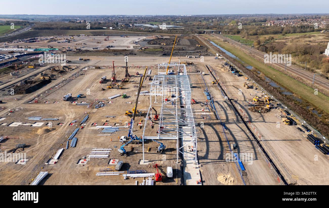 Grues travaillant sur la structure en acier sur le chantier de construction, avec le paysage environnant visible en vue aérienne Banque D'Images
