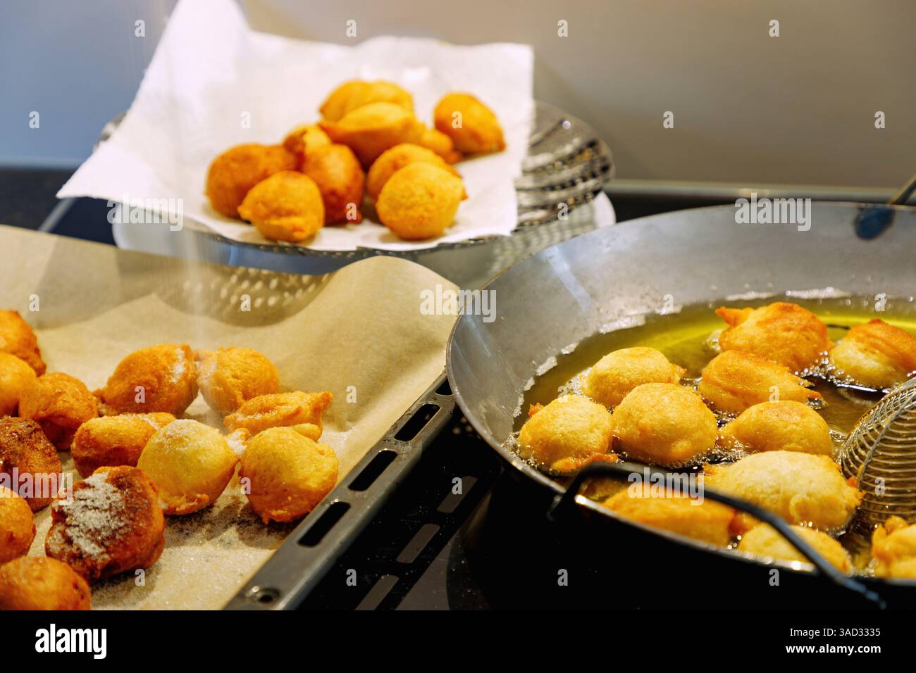 Préparation des boules de quark : boules de Quark flottant dans la graisse chaude, boules de quark s'égouttant sur un torchon et biscuits de quark saupoudrés de sucre sur du papier sulfurisé Banque D'Images