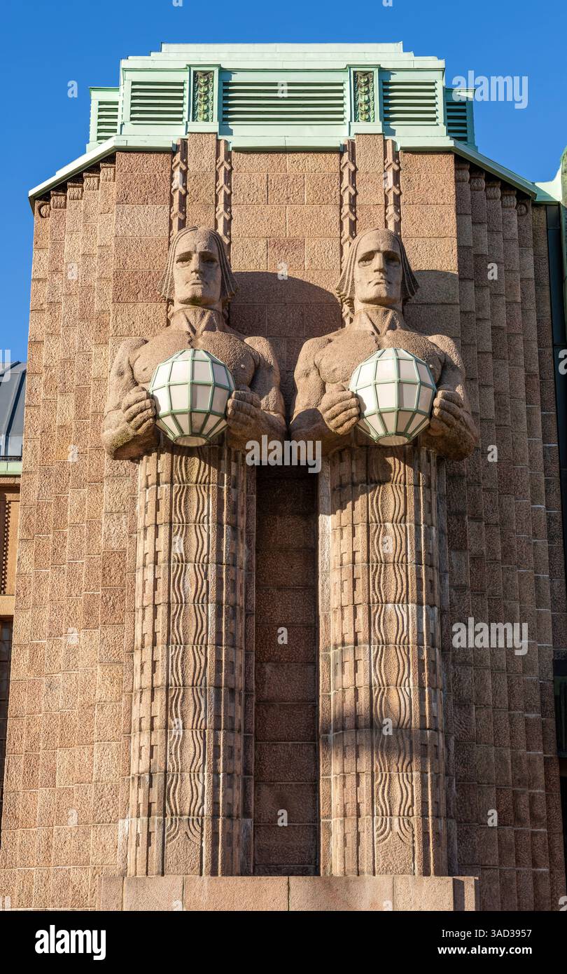 Helsinki, la gare ferroviaire d'Helsinki est un point de repère bien connu de la ville. Le bâtiment présente des éléments de l'Art Nouveau et du néoclassicisme et a été inauguré en 1919. Les personnages sur la façade à côté de l'entrée principale, appelés Kivimiehet en finnois, tiennent chacun un globe en verre dans leurs mains. Banque D'Images