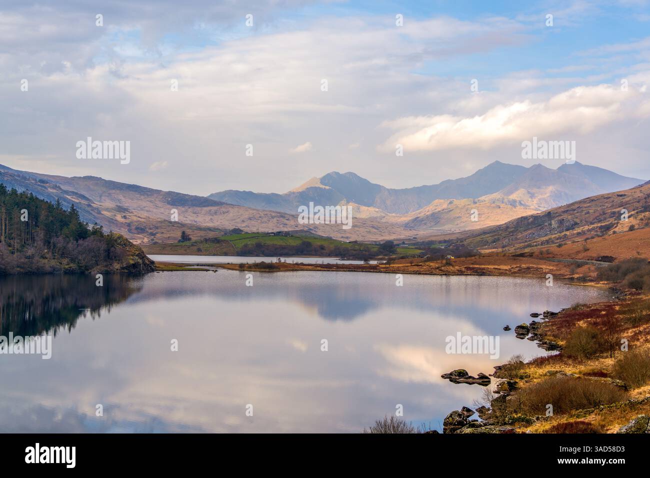 Le Llyn Gwynant de Snowdonia reflète un majestueux panorama montagneux sous un ciel gallois vibrant, capturant la beauté sereine du nord du pays de Galles. Banque D'Images