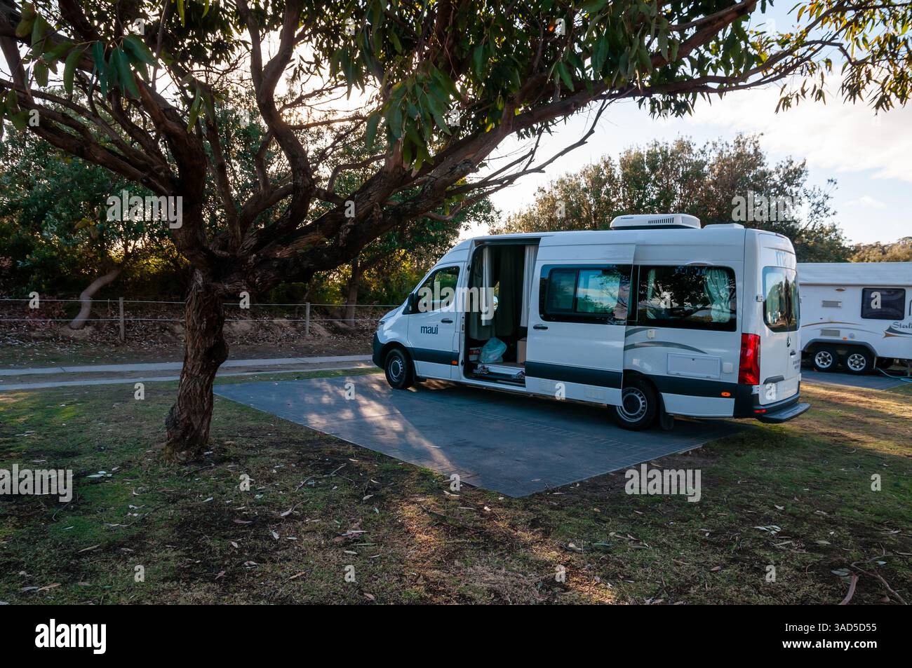 Maui Campervan garé au camping, aventure de voyage en plein air, location camping-car sous les arbres, journée ensoleillée, plage de Pambula, Australie Banque D'Images