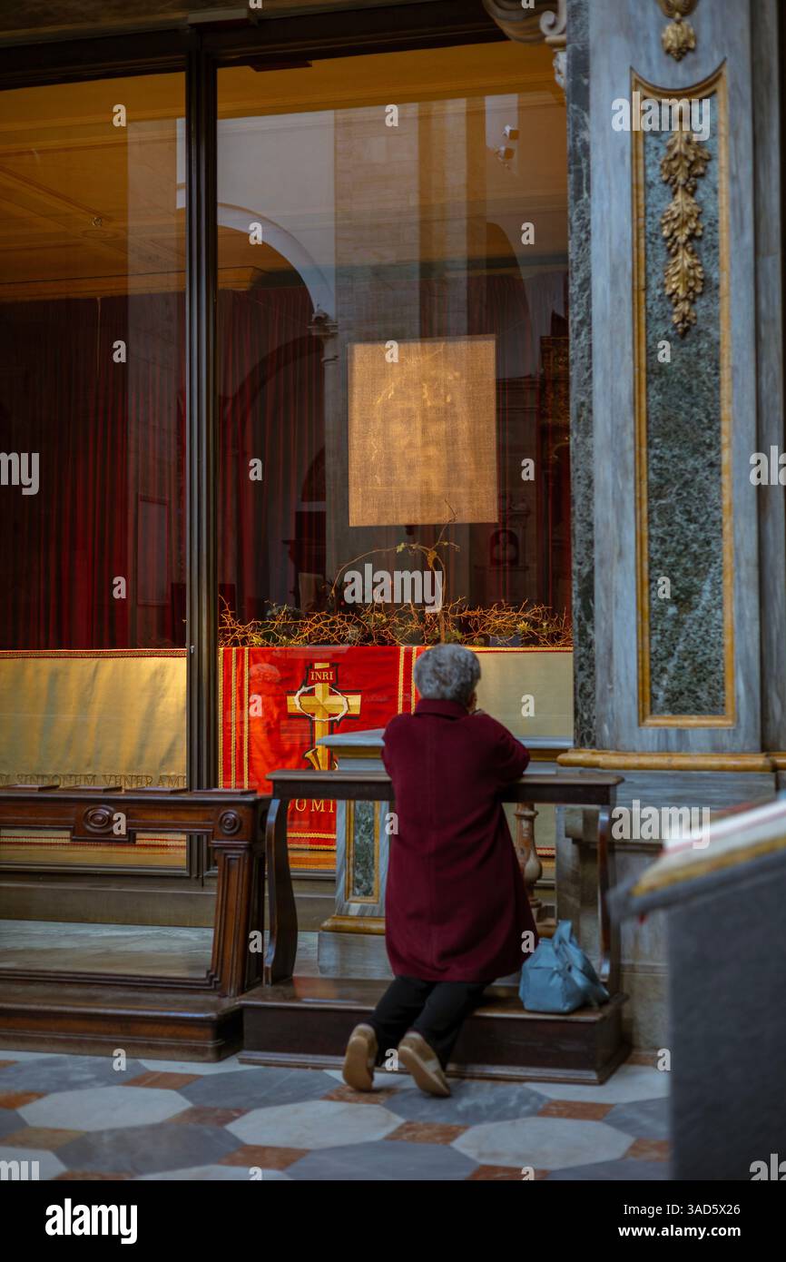 Une femme s'agenouille en prière devant la vitrine contenant le Suaire de Turin (Sindone di Torino) à l'intérieur de la cathédrale de Turin, en Italie. Banque D'Images