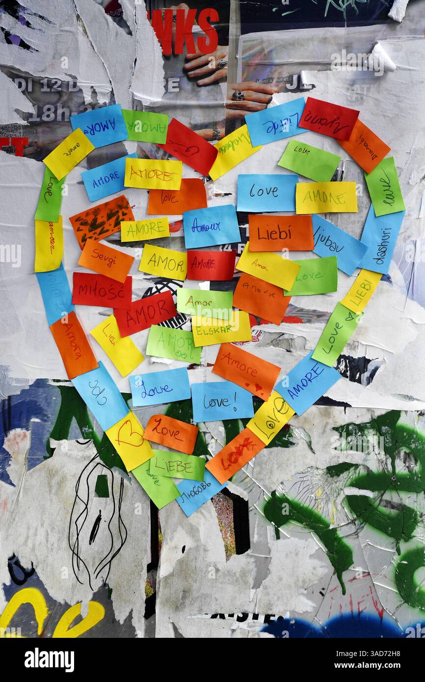 Mot LOVE écrit dans toutes les langues avec des notes adhésives sur un mur dans la rue de Paris - France Banque D'Images