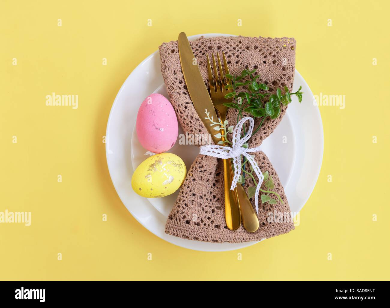 Joyeuses Pâques. Concept de célébration de Pâques. Vue de dessus verticale serviette vide plaque blanche et jaune, oeufs de Pâques, sur fond jaune isolé. Copier spac Banque D'Images