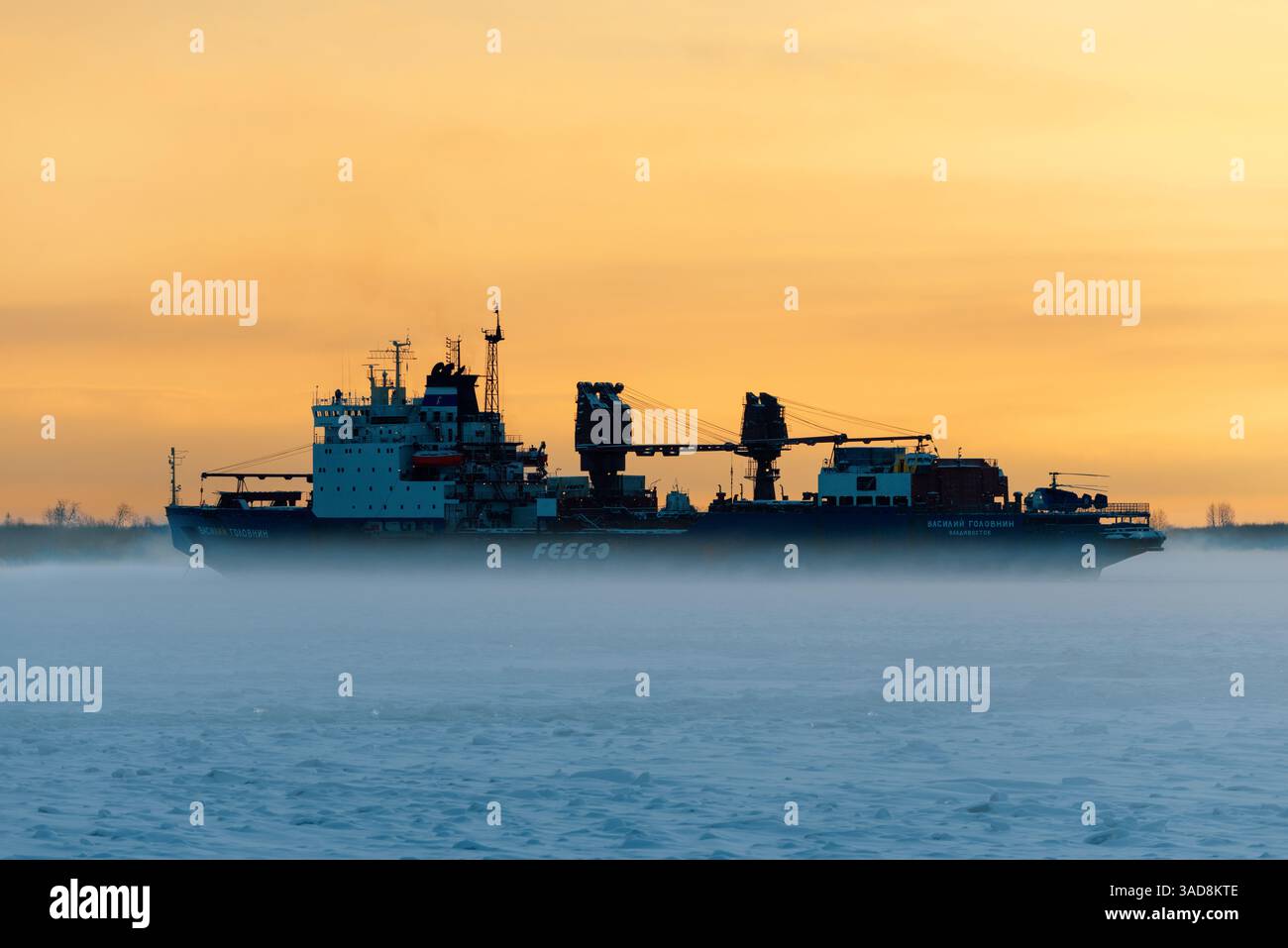Le cargo brise-glace 'Vasiliy Golovnin' est ancré dans la glace dans le brouillard au coucher du soleil Banque D'Images