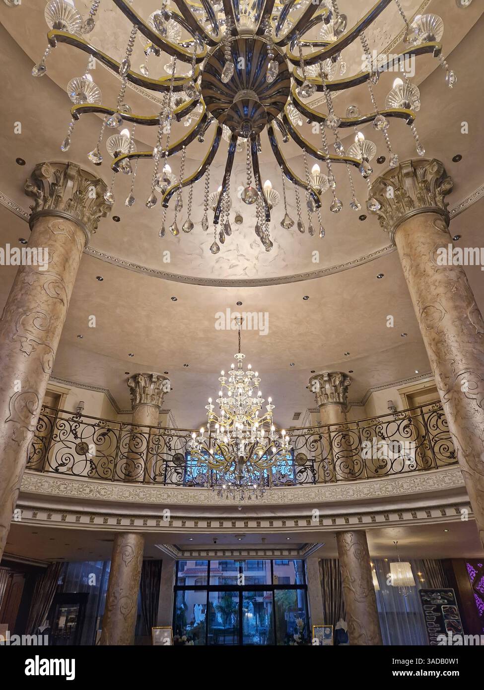 Intérieur opulent du hall avec de grands piliers ornés et de grands lustres suspendus au plafond détaillé. Cadre luxueux du hall d'entrée dégageant l'élégance - Image de stock capturée avec un smartphone