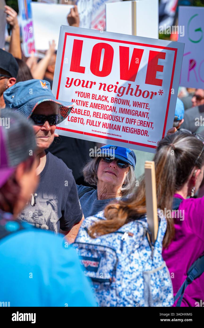 Une femme plus âgée tient un panneau sur l'amour de son voisin avec une liste inclusive de catégories à la manifestation Hands-Off de 50501, tenue au Capitole. Banque D'Images