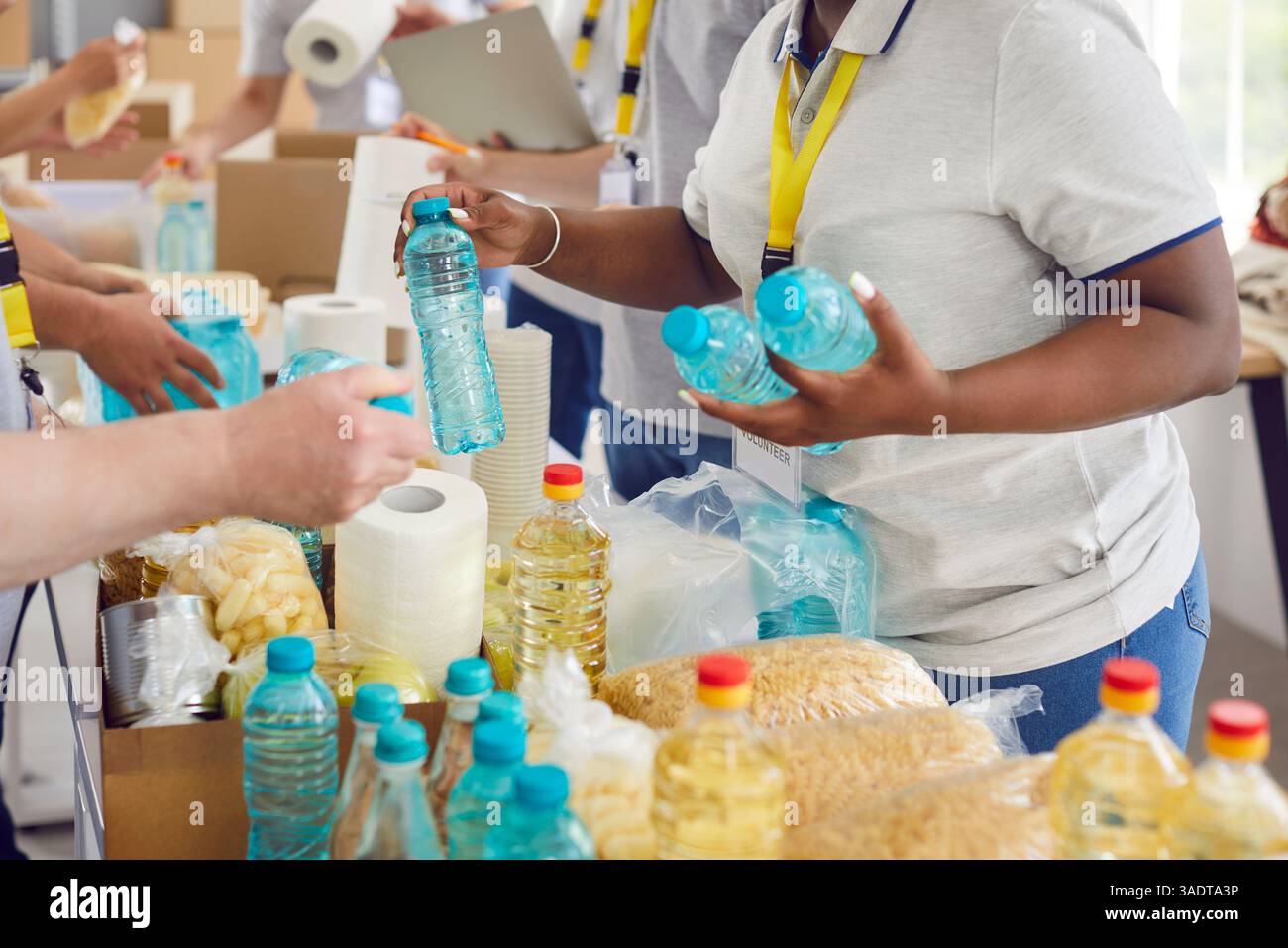 Divers bénévoles regroupent le tri des dons de denrées alimentaires dans des boîtes en carton pour la collecte de nourriture caritative Banque D'Images