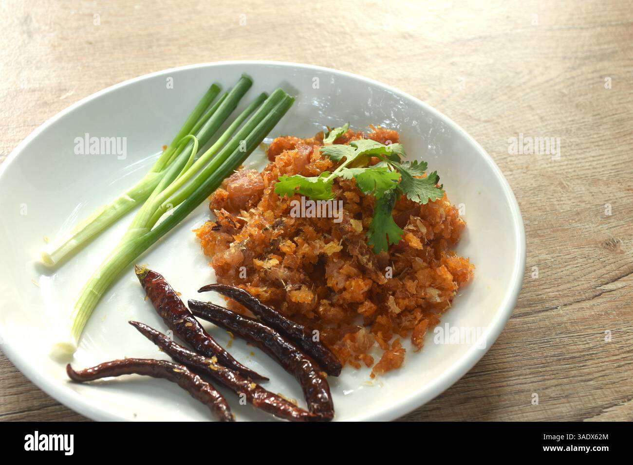 hacher le poisson mariné sec frit a goût aigre et salé piment de garniture avec tranche d'oignon de printemps sur l'assiette Banque D'Images