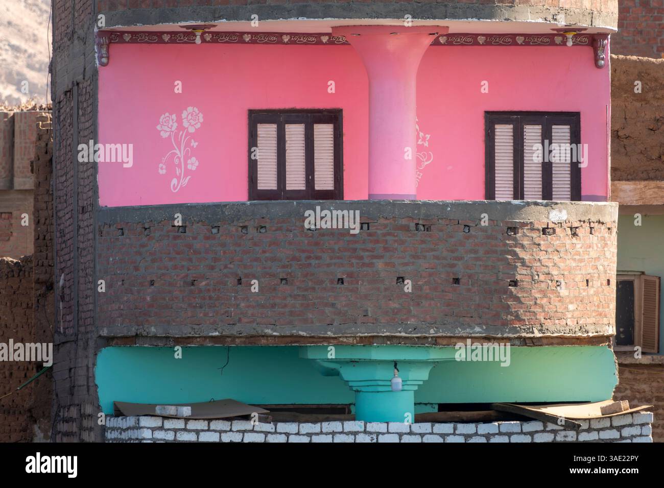 Un immeuble étroit montrant deux balcons empilés, l'un décoré et peint en rose avec des motifs floraux, l'autre turquoise pâle Banque D'Images