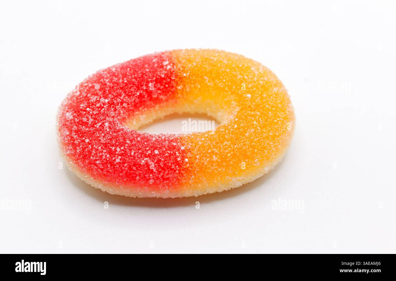 Bonbon à anneaux gommeux enrobés de sucre jaune et rouge avec un extérieur poussiéreux et une forme de beignet. Banque D'Images