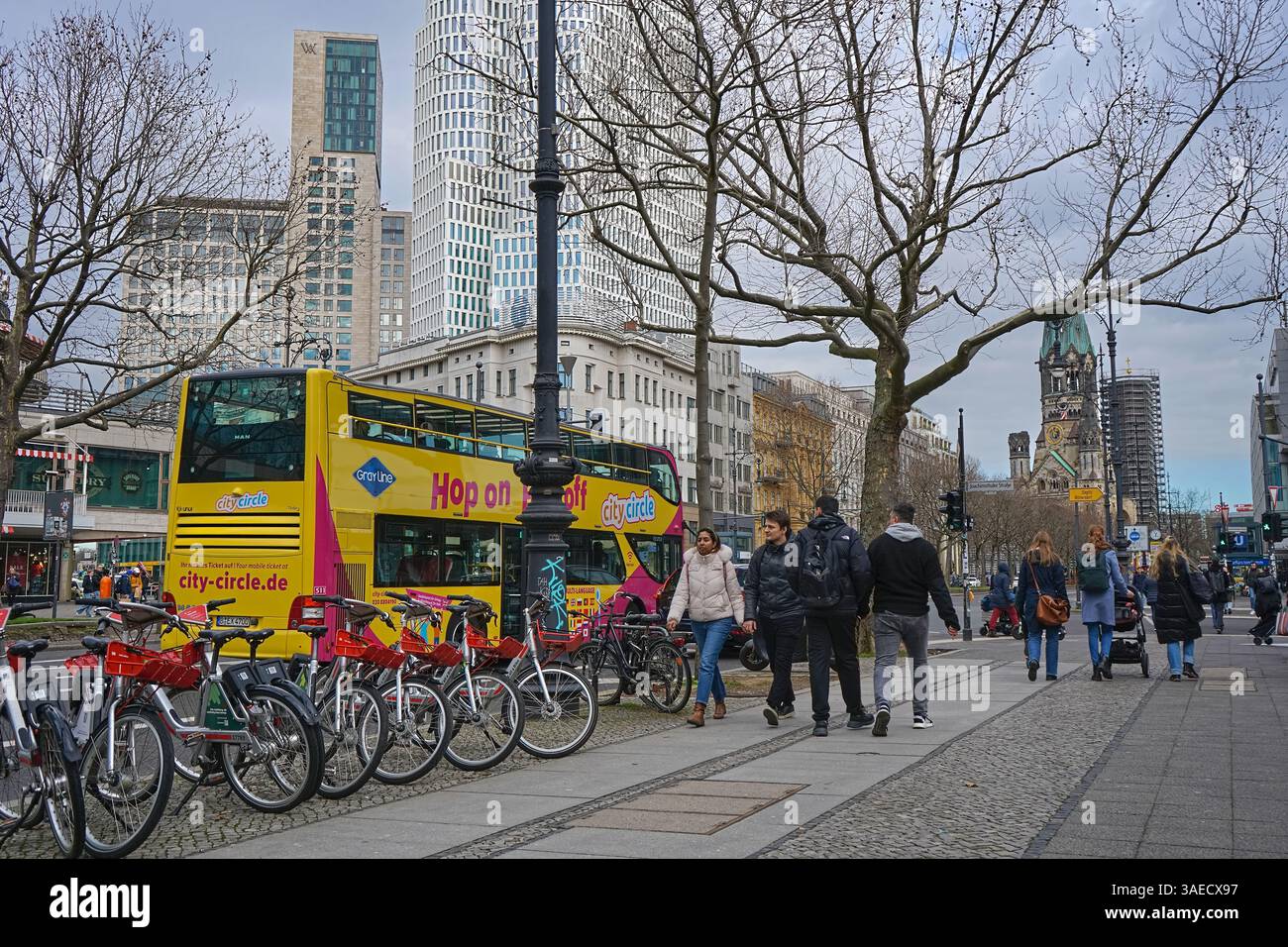 Journée d'hiver nuageuse sur Kudamm Berlin avec bus à arrêts multiples, piétons et église commémorative Kaiser Wilhelm au loin Banque D'Images
