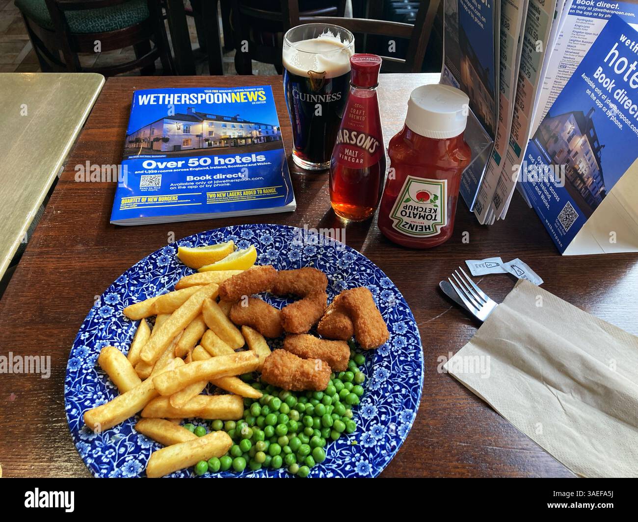 Bar-restaurant Wetherspoon servant des Scampi and Chips avec des petits pois et une pinte de Guinness, Royaume-Uni Banque D'Images