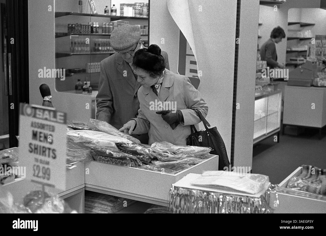 AJAXNETPHOTO. 1975. HAVANT (ANGLETERRE). - COUPLE PLUS ÂGÉ MAGASINANT DANS LE SUPERMARCHÉ CO-OP REGARDANT LES VÊTEMENTS. PHOTO :JONATHAN EASTLAND/AJAX REF :EPS202608 65. Banque D'Images