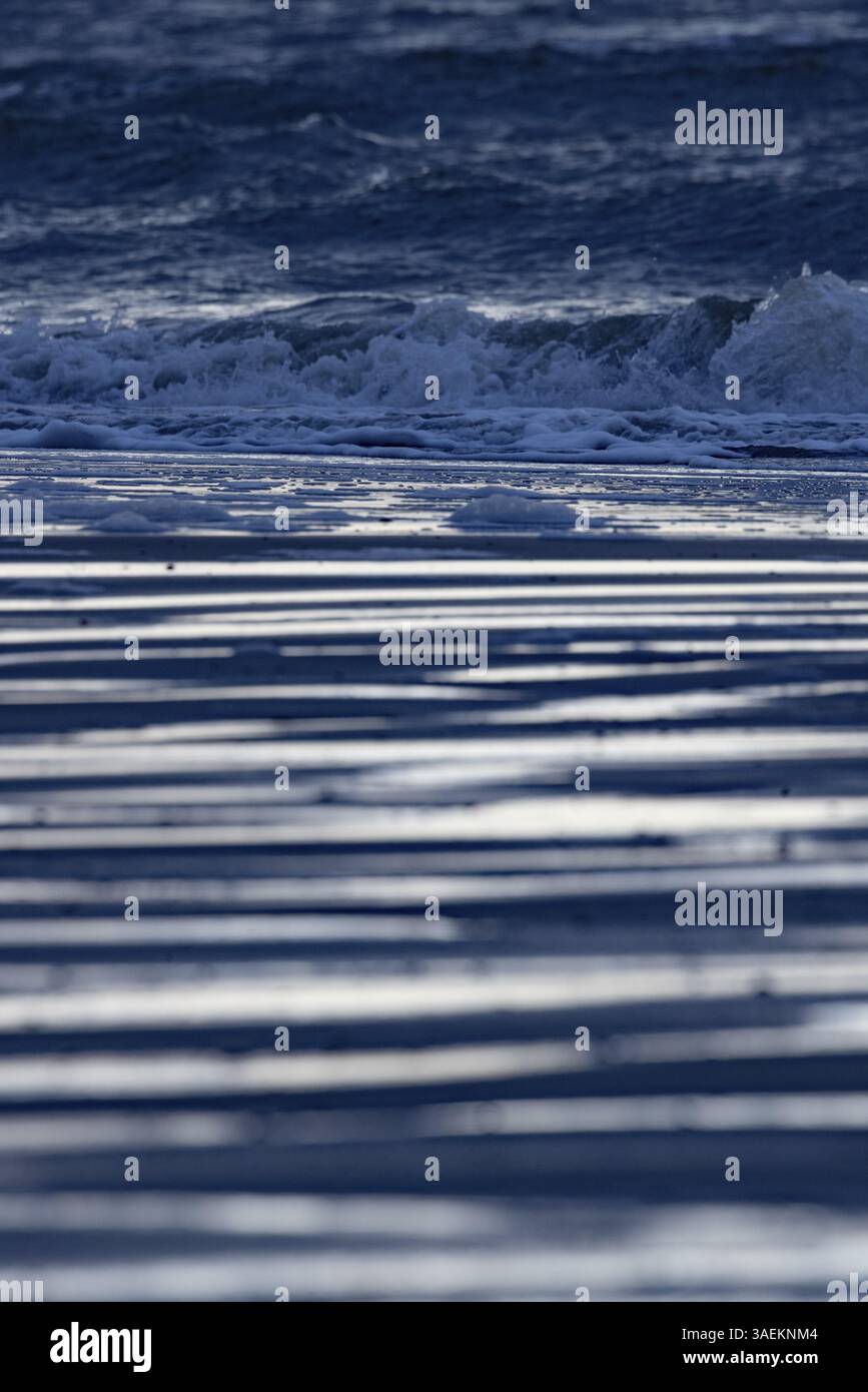 Des vagues mousseuses frappent la plage sous une lumière réfléchissante, Groede, Zélande, pays-Bas Banque D'Images