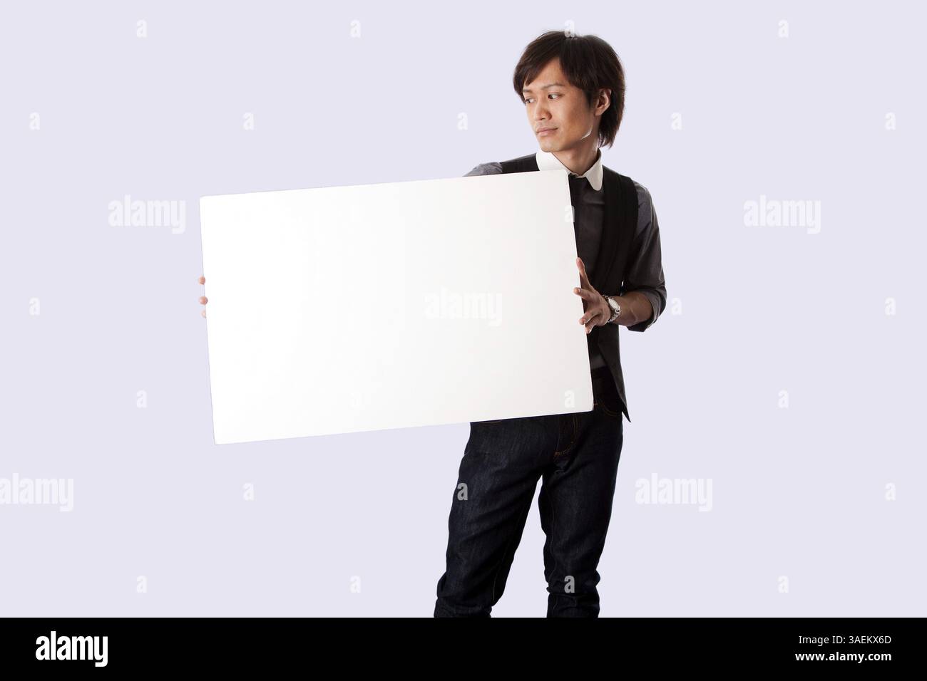 Jeune homme d'affaires asiatique étudiant debout tenant un tableau blanc blanc et le regardant, isolé, New York, États-Unis, Amérique du Nord Banque D'Images