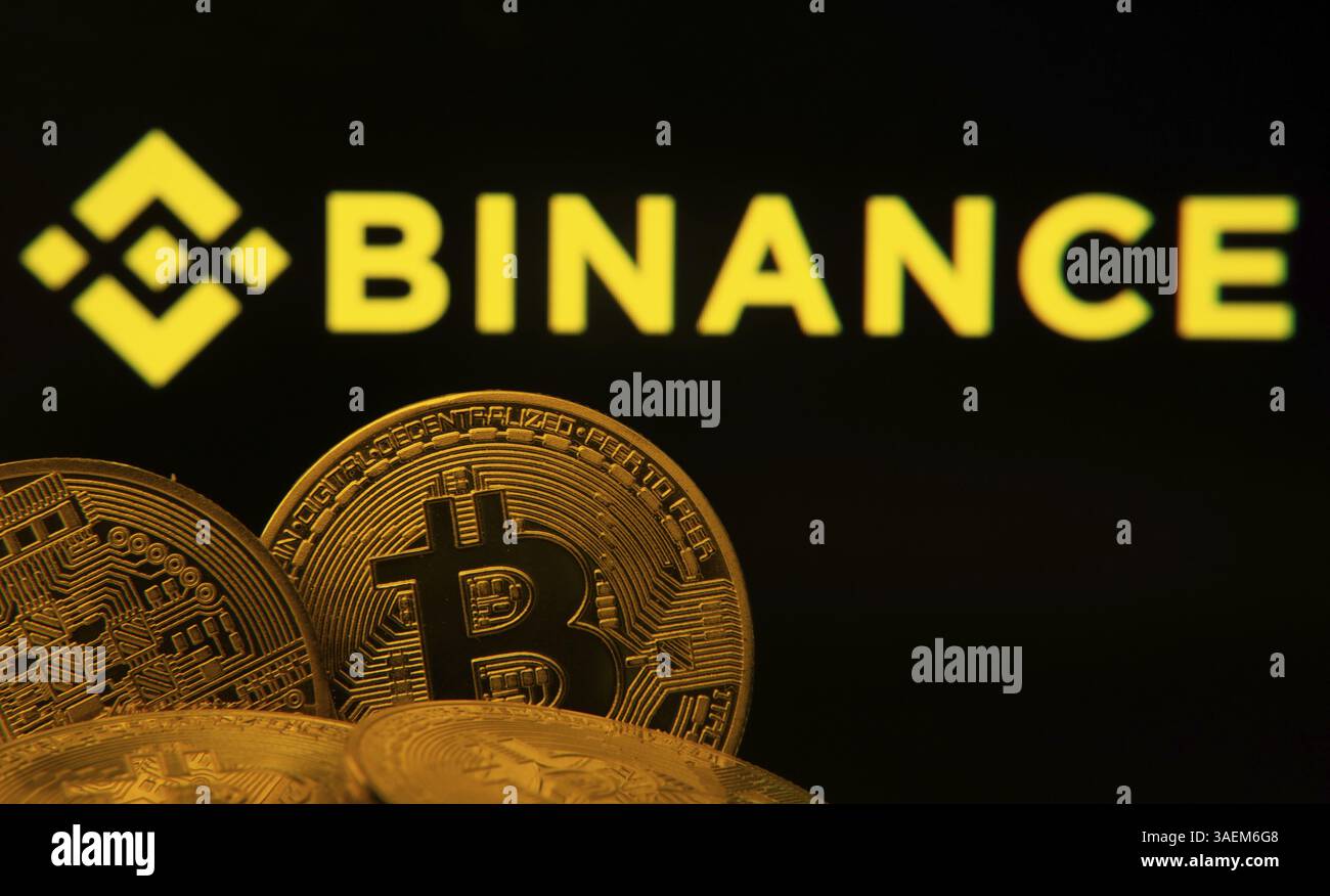 Gros plan de Bitcoin coins avec le logo Binance visible sur un écran en arrière-plan Banque D'Images