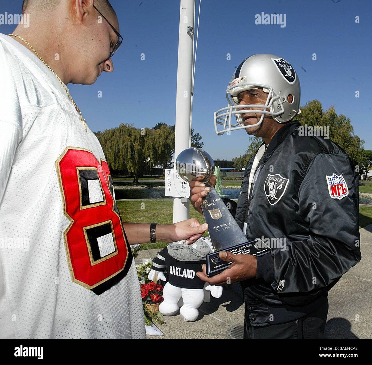 9 mai 1996 - Oakland, CA, États-Unis - Mark Sandoval, fan des 49ers de San Francisco, à gauche, regarde de plus près une réplique du trophée du Super Bowl XI que Troy Parkins, fan des Raiders d'Oakland, tient devant un mémorial de fortune pour Al Davis, propriétaire des Raiders d'Oakland, au siège des Raiders à Alameda, Californie, le samedi 8 octobre 2011. Al Davis, propriétaire des Raiders, qui a connu une carrière de 60 ans dans le football, est décédé samedi. Il avait 82 ans. (Crédit image : © Ray Chavez/Oakland Tribune/MCT/ZUMAPRESS.com) Banque D'Images