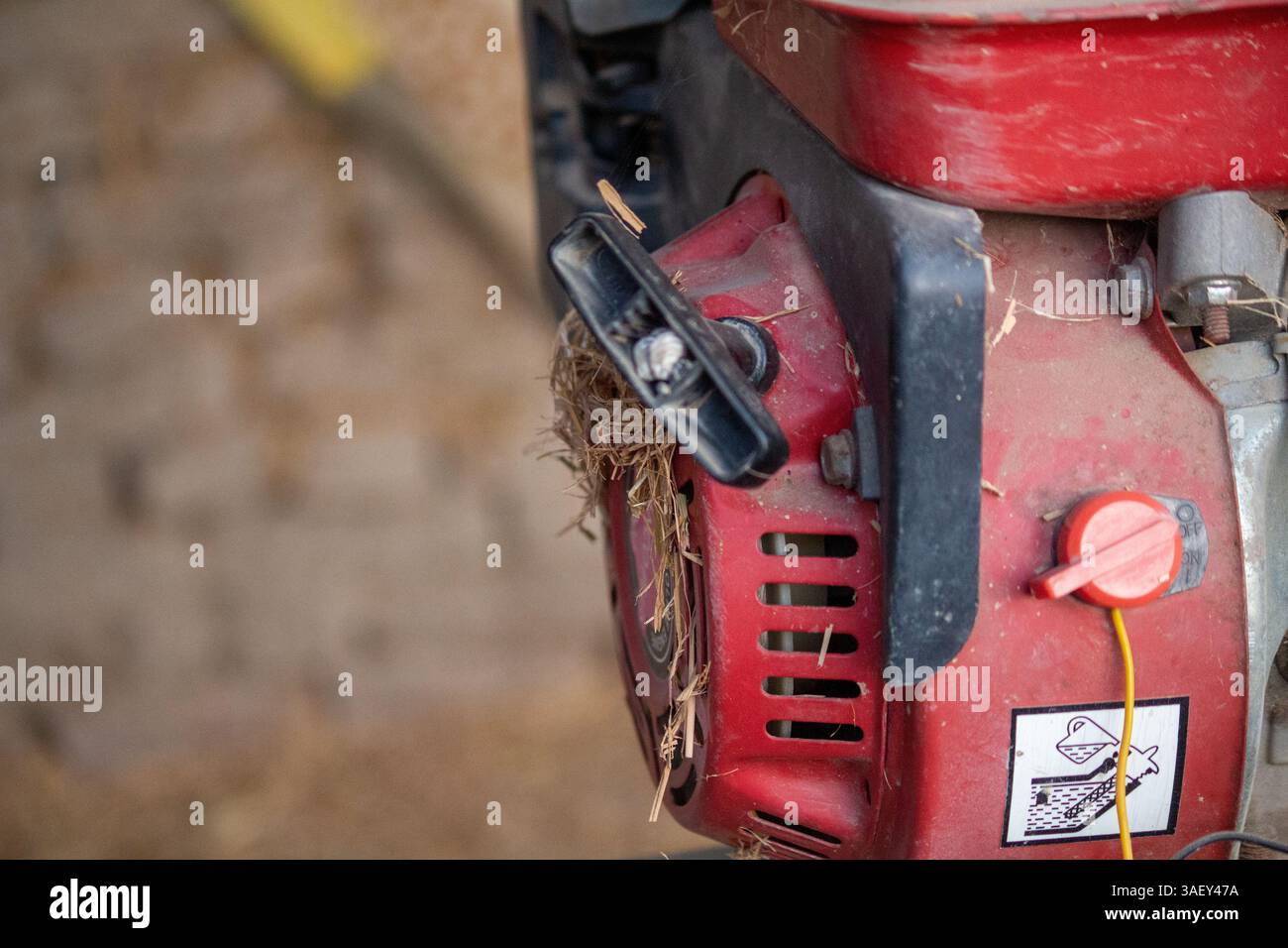 Gros plan d'un moteur à essence rouge avec de la poussière et des débris dans un atelier Banque D'Images