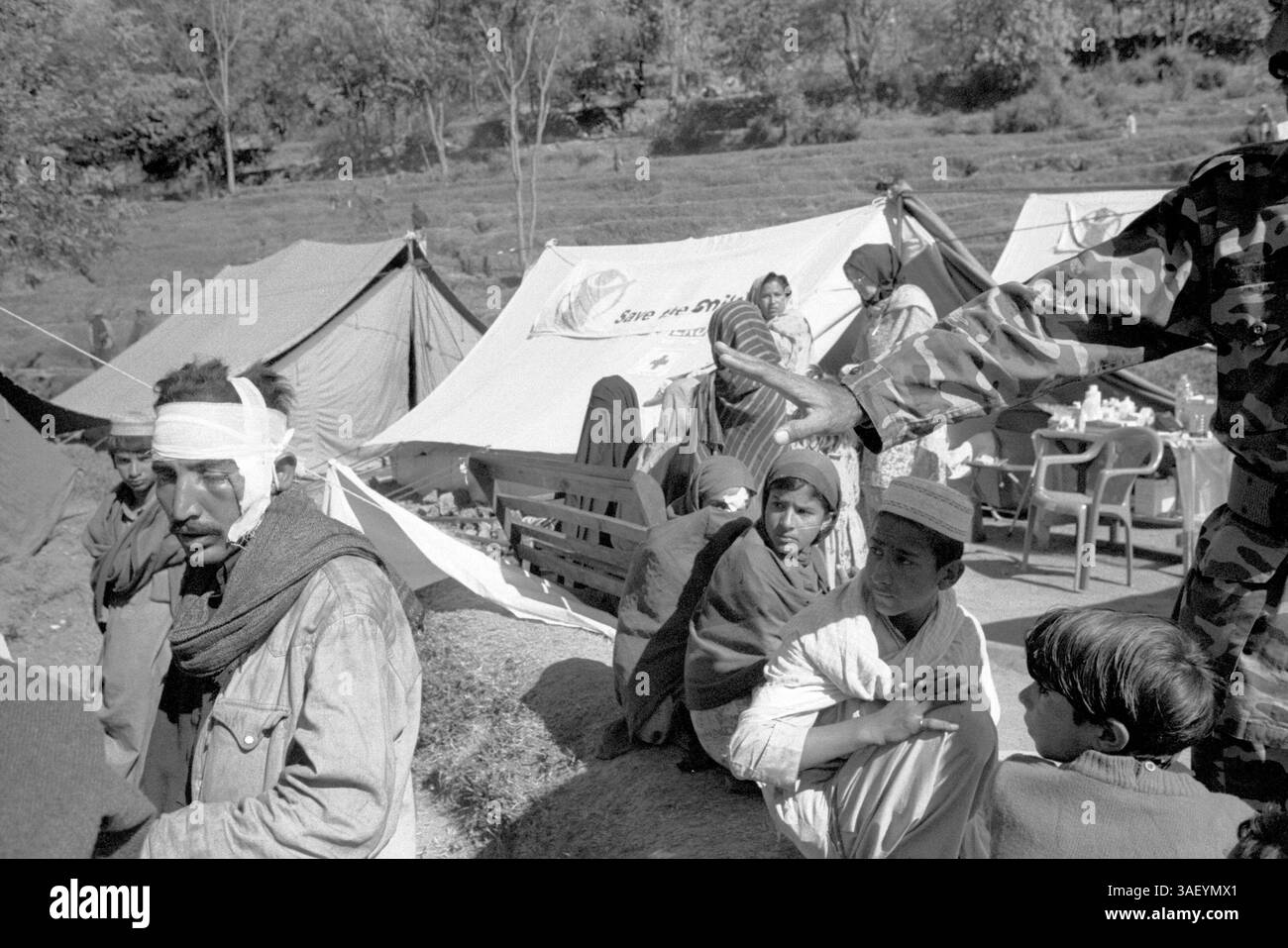10 janv. 2006 ; Bana, PAKISTAN ; (PHOTO DE DOSSIER : novembre 2005) des survivants du tremblement de terre attendent des soins médicaux dans une clinique de terrain gérée par Save the Children. Des patrouilles militaires contrôlent la foule. Un père réconforte son fils pendant qu'ils attendent. Plus de 80 000 personnes ont été tuées le 8 octobre 2005, lorsque le séisme de magnitude 7,6 a dévasté la région, rendant plus de 3,5 millions de personnes sans abri. Maintenant, plus de trois mois après le séisme, le rude hiver himalayen signifie que les températures nocturnes sont bien en dessous de zéro. Les travailleurs humanitaires sont préoccupés par les 3 millions de survivants qui subissent un temps glacial à FLI Banque D'Images