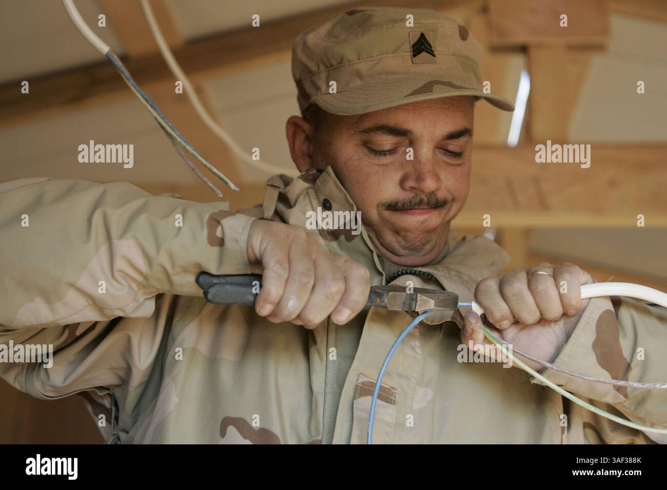 11 janvier 2005 ; Camp Taqaddum, Irak ; le sergent DANIEL L. WOMACK, un natif de Wilburton, Oklahoma, âgé de 38 ans, prépare des fils pour un projet d'éclairage à l'intérieur d'une cabane d'Asie du Sud-Ouest qu'il aide à construire au Camp Taqaddum, Irak, le 11 janvier 2005. Womack est électricien au sein du 120th Engineer combat Battalion, une unité de la Garde nationale de l'Oklahoma qui a construit 122 cabanes pour les Marines basés au Camp Taqaddum, en Irak. L'unité, qui a fourni des services d'ingénieurs allant du remplissage de trous à l'aide au nettoyage de Falloujah, quittera bientôt l'Iraq après un déploiement d'un an. Banque D'Images
