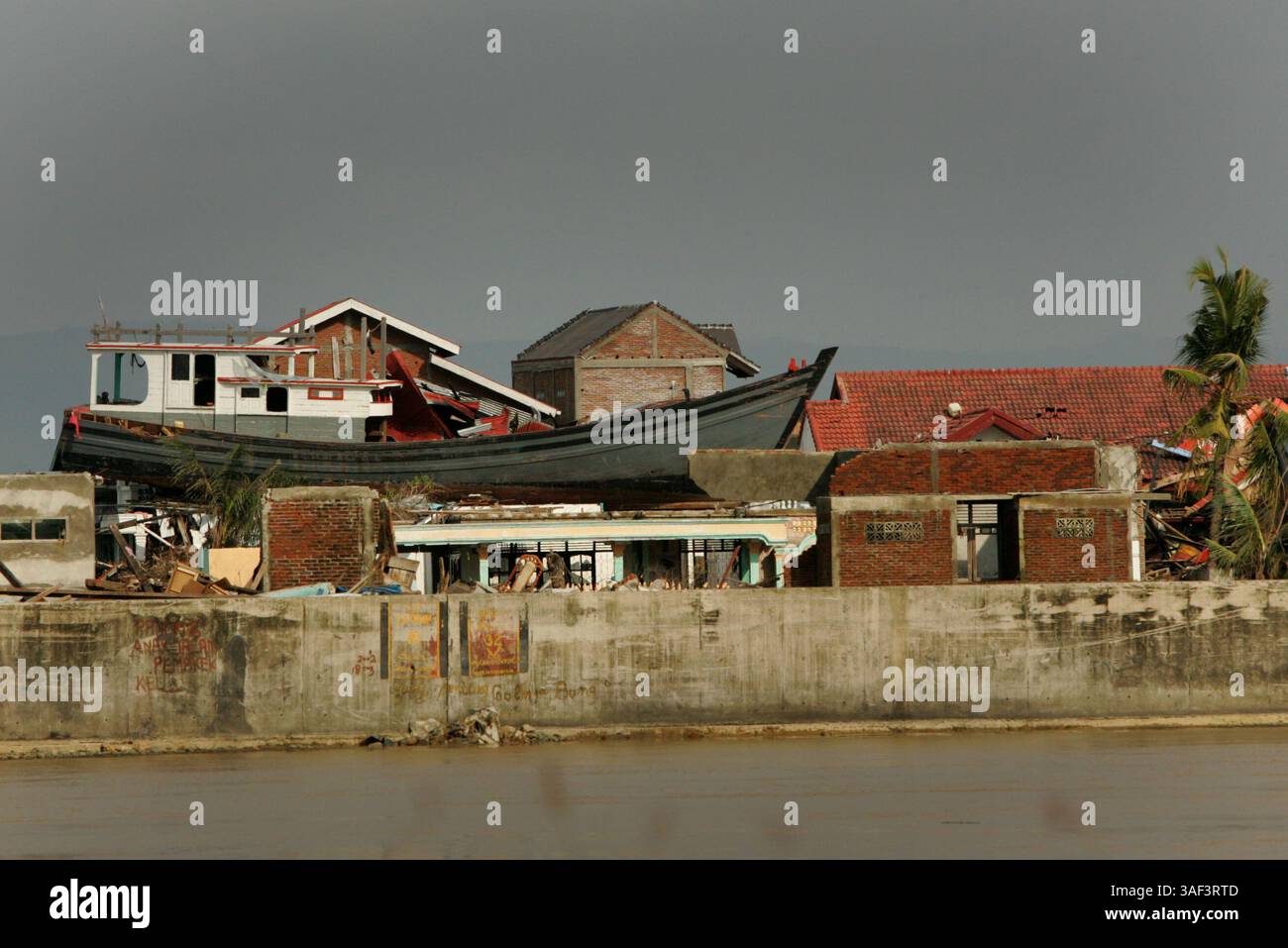 11 décembre 2005 ; Banda Aceh, INDONÉSIE ; Un grand bateau de pêche se trouve au sommet d'une maison à Banda Aceh, déposée là par le tsunami. Les résidents de la maison ont survécu, avec 42 voisins, en grimpant dans le bateau alors que le tsunami faisait rage autour d'eux. Le bateau reste sur ce qui reste de la maison et la femme vit à quelques kilomètres de là avec des parents, mais visite son ancienne maison tous les jours. L'endroit maintenant célèbre est un favori des touristes curieux et des travailleurs humanitaires. Plus de 250 000 personnes sont mortes dans 11 pays après un tsunami dévastateur qui a frappé l'Asie du Sud le 26 décembre 2004. L'onde sismique résultait d'un magnitu de 9,0 Banque D'Images
