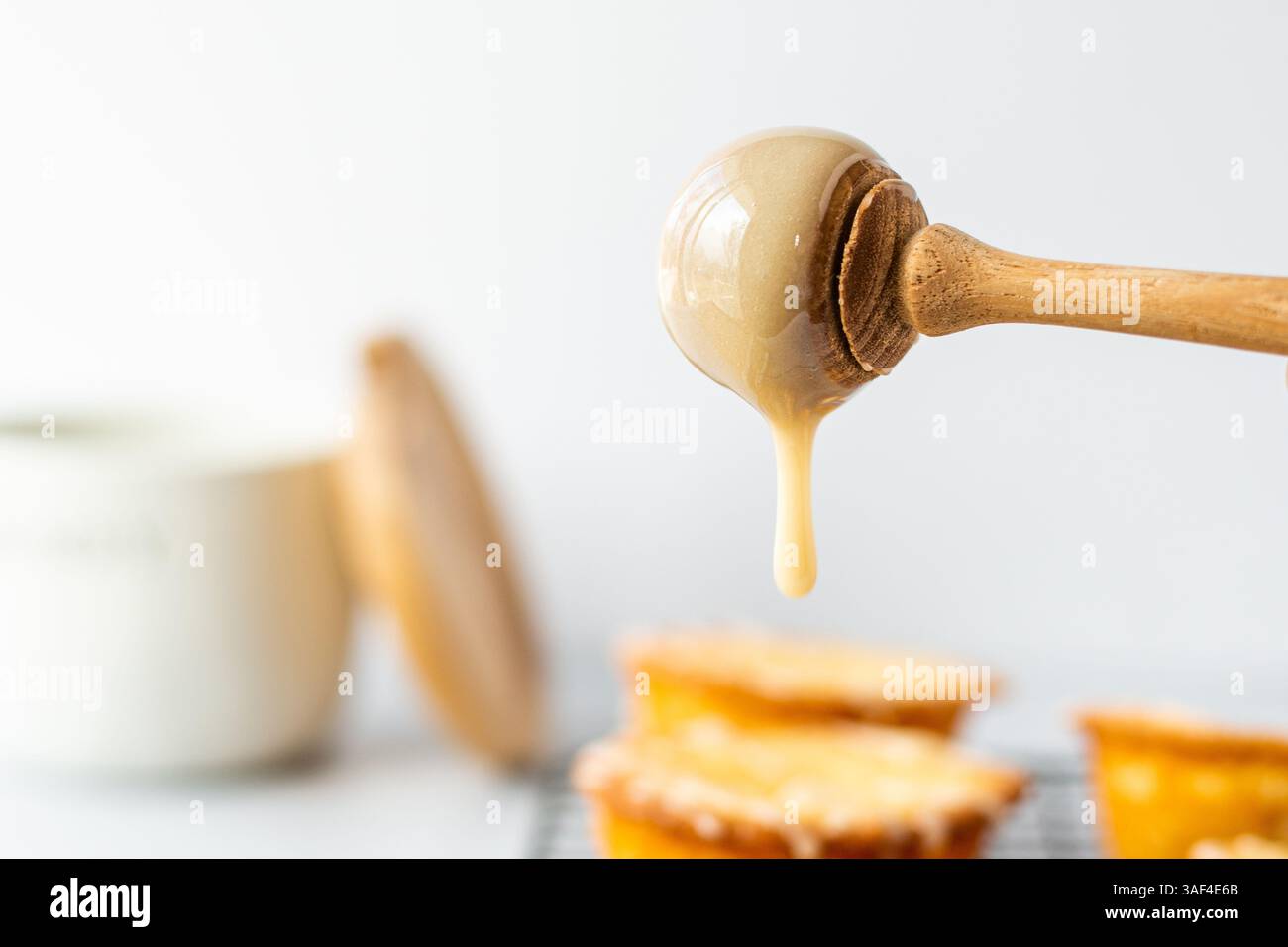 Miel s'égouttant d'une trempette de miel sur des muffins sucrés Banque D'Images