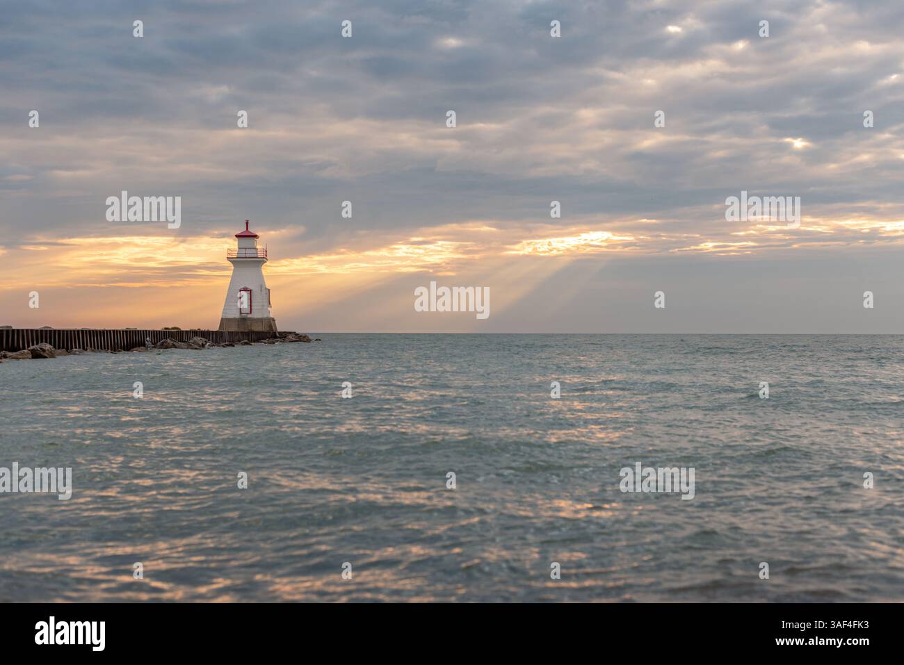 Beau phare se trouve au bout de la jetée avec le ciel de coucher de soleil sombre Banque D'Images