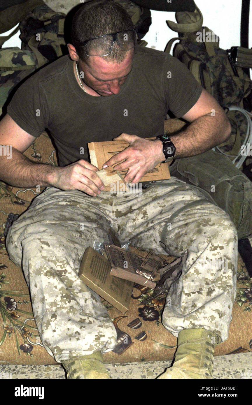 Février 02, 2005 ; Fallujah, Irak ; lance Cpl TIM C. ''TIMMY 249'' CASTELL, 23 ans, natif d'Arlington, Texas, qui sert de mitrailleur automatique pour la compagnie I, 3e bataillon, 4e régiment de Marines, équipe de combat régimentaire 1, ouvre un repas prêt à manger dans sa chambre à Fallujah, Irak. Les Marines d'infanterie subsistent sur MREÕs pour la plupart de leur temps déployé. Banque D'Images