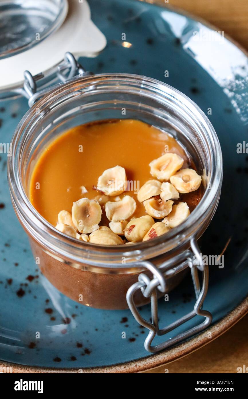 Une mousse onctueuse et riche au chocolat et aux noisettes servie dans un bocal, garnie de noisettes finement hachées. Banque D'Images