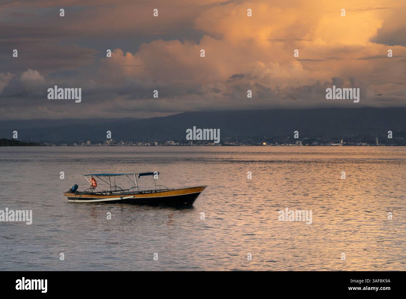 Un petit bateau de pêche traditionnel sur la côte de l'île de Sulawesi pendant le coucher de soleil coloré Banque D'Images