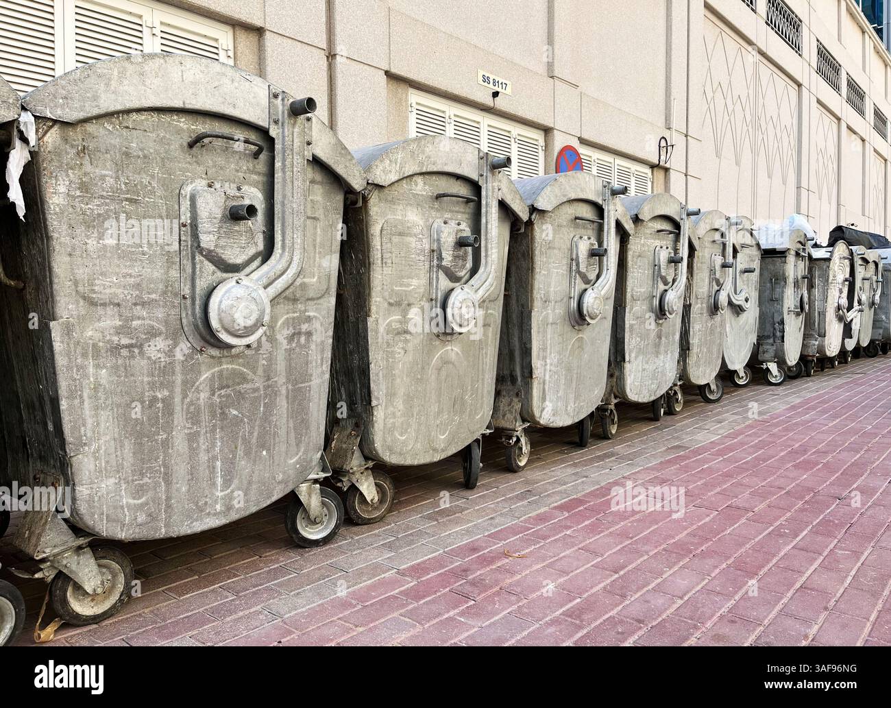 Rangée de vieilles poubelles en métal sur roulettes le long du trottoir de la ville. Gestion des déchets, services municipaux. Dubaï, Émirats arabes Unis, le 7 avril 2025 Banque D'Images