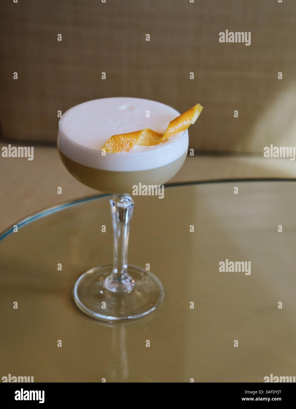 Cocktail de whisky aigre sophistiqué servi dans un verre coupé, surmonté d'une couche de mousse crémeuse et garni d'une touche d'écorce d'orange. Boisson de bar moderne Banque D'Images