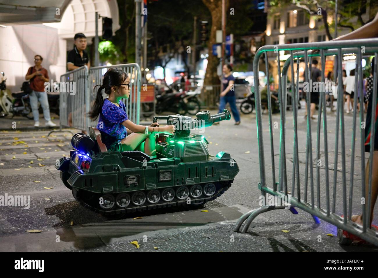 VIETNAM, ville de Hanoi, guerre du Vietnam aujourd'hui, les enfants conduisent le jouet de réservoir en plastique mobile dans la rue la nuit / Kinder fahren Spielzeug Panzer aus Plastik Banque D'Images