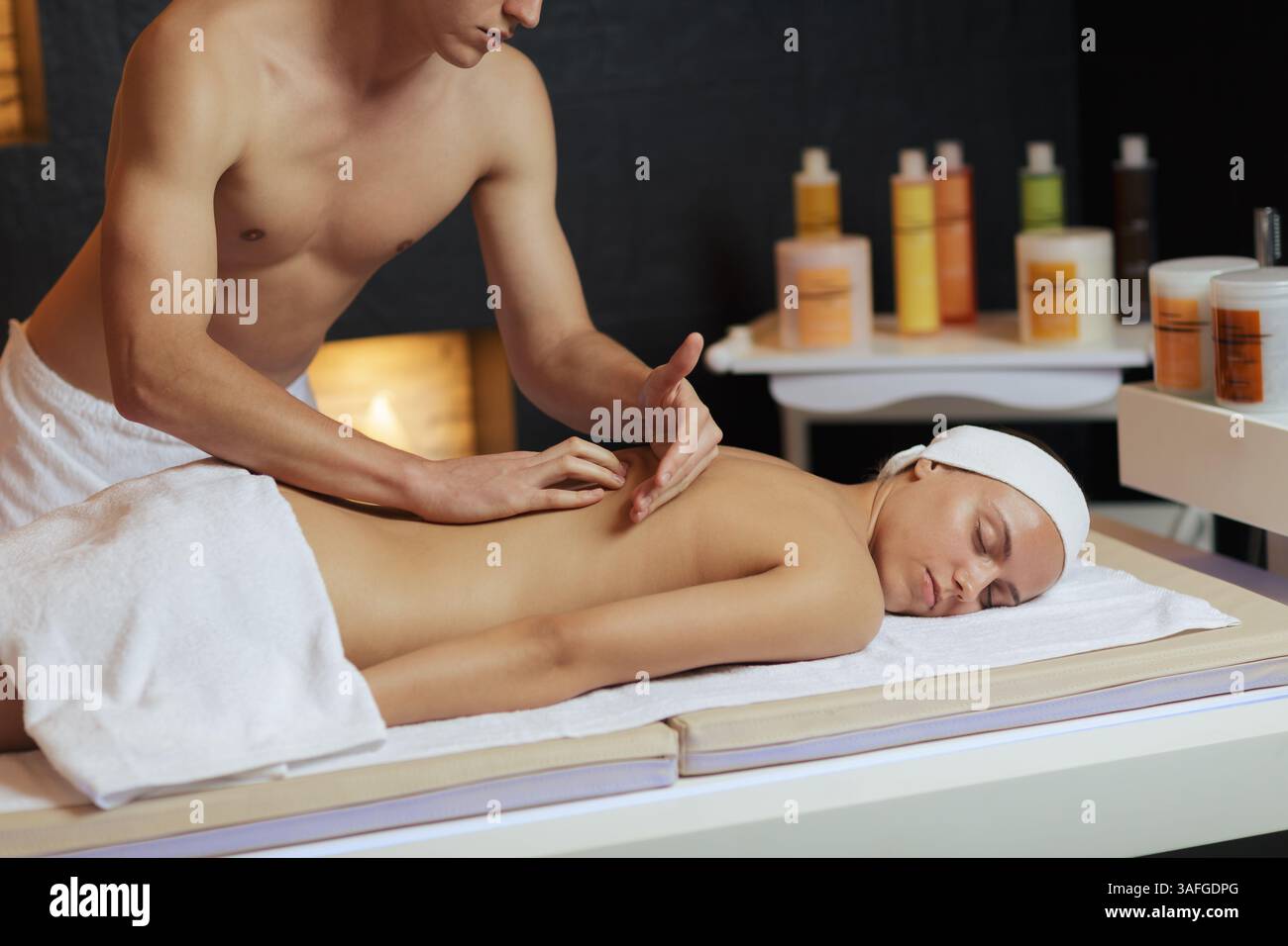 Thérapeute masculin professionnel effectuant un massage du dos des tissus profonds sur une femme détendue dans un centre de spa de luxe. Banque D'Images