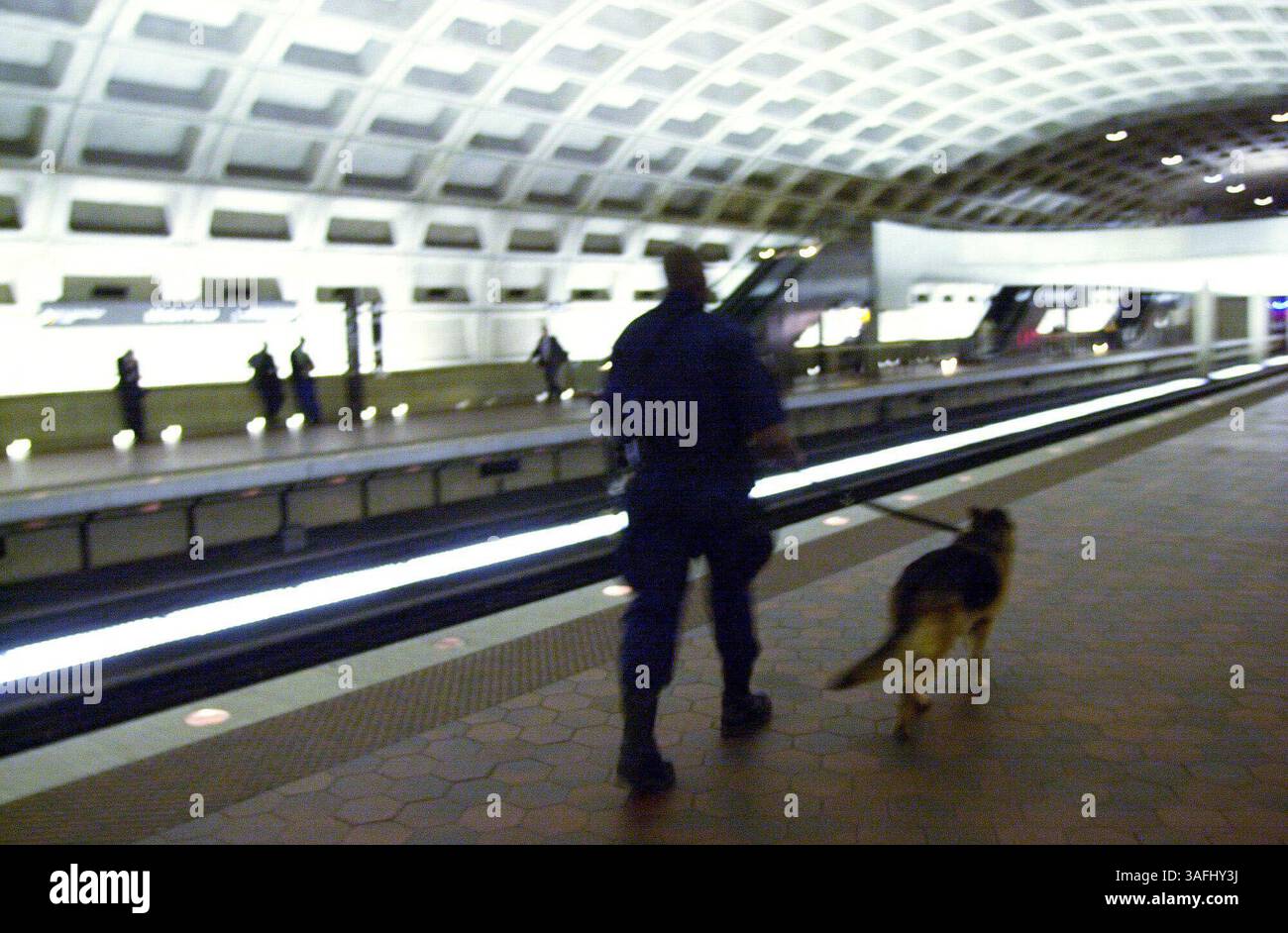 Un policier de DC Metro et son Shepard allemand patrouillent la région tandis que les navetteurs prennent le train du métro à la station de métro L'enfant dans le sud-ouest de Washington DC, le 14 avril 2003. Pour améliorer la sécurité des trains et des bus DC, les responsables de DC Metro et de la sécurité intérieure ont élaboré un plan pour tous les navetteurs sur la façon de planifier et de se préparer aux urgences. Le plan comprend des informations importantes sur l'interphone d'urgence de Metro et les instructions d'évacuation d'urgence, ainsi que la page Web de Metro pour trouver des itinéraires alternatifs. (Crédit image : The Washington Times/ZUMAPRESS.com) Banque D'Images