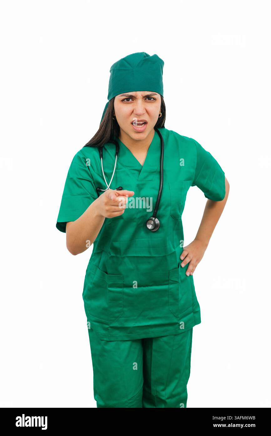 Chirurgien féminin latin portant des gommages verts et stéthoscope gronde quelqu'un tout en pointant son doigt, exprimant la réprimande et l'autorité sur un nettoyage Banque D'Images