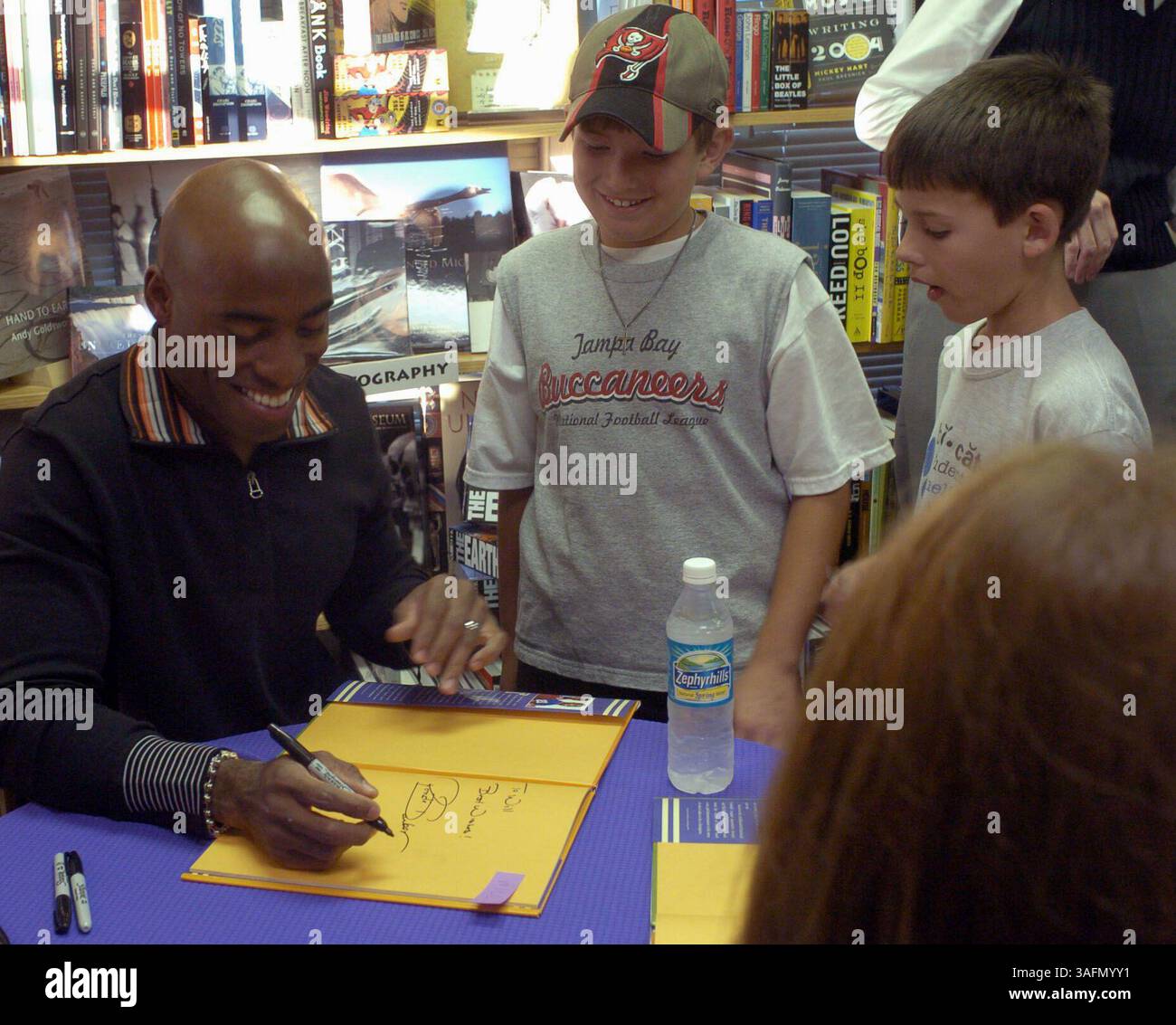 Pour Sunday Red zone dernière page et histoire de Joanne Korth, photos de ronde Barber à sa signature de livre chez Inkwood Books, 216 S. Armenia à Tampa mercredi (12/1/04). Le livre, du côté de mon frère, a été écrit par lui et son frère Tiki.***photo 1. Ronde Barber signe un des nombreux livres lors de sa signature de livre. Les jeunes lecteurs sont, de gauche à droite : Will McClintock (ID du parent), 9 ans et son ami A.J. Valdes (image crédit : St Petersburg Times/ZUMAPRESS.com) Banque D'Images