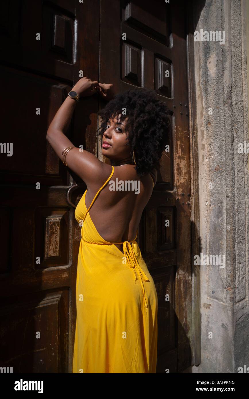 Portrait d'une belle femme portant une robe jaune debout par une vieille porte en bois brun. Concept de voyage de personne heureuse. Banque D'Images